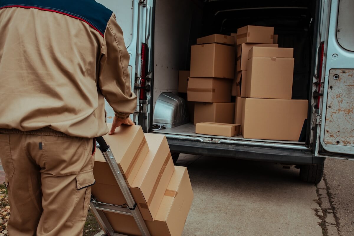 Delivery man packing cardboard boxes in van