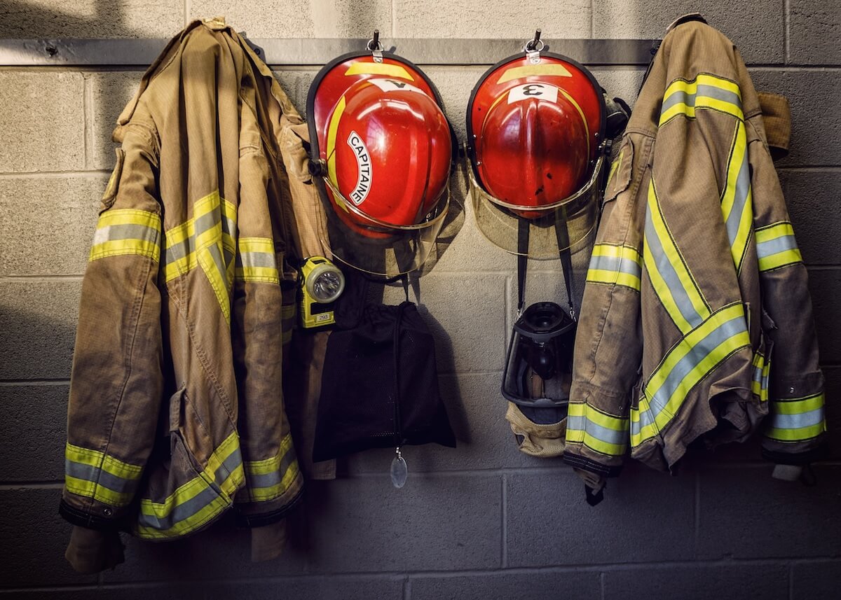 Firefighter jackets and helmets hanging on wall