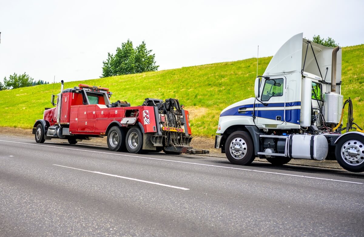 Towing truck getting ready to haul large tractor trailer truck